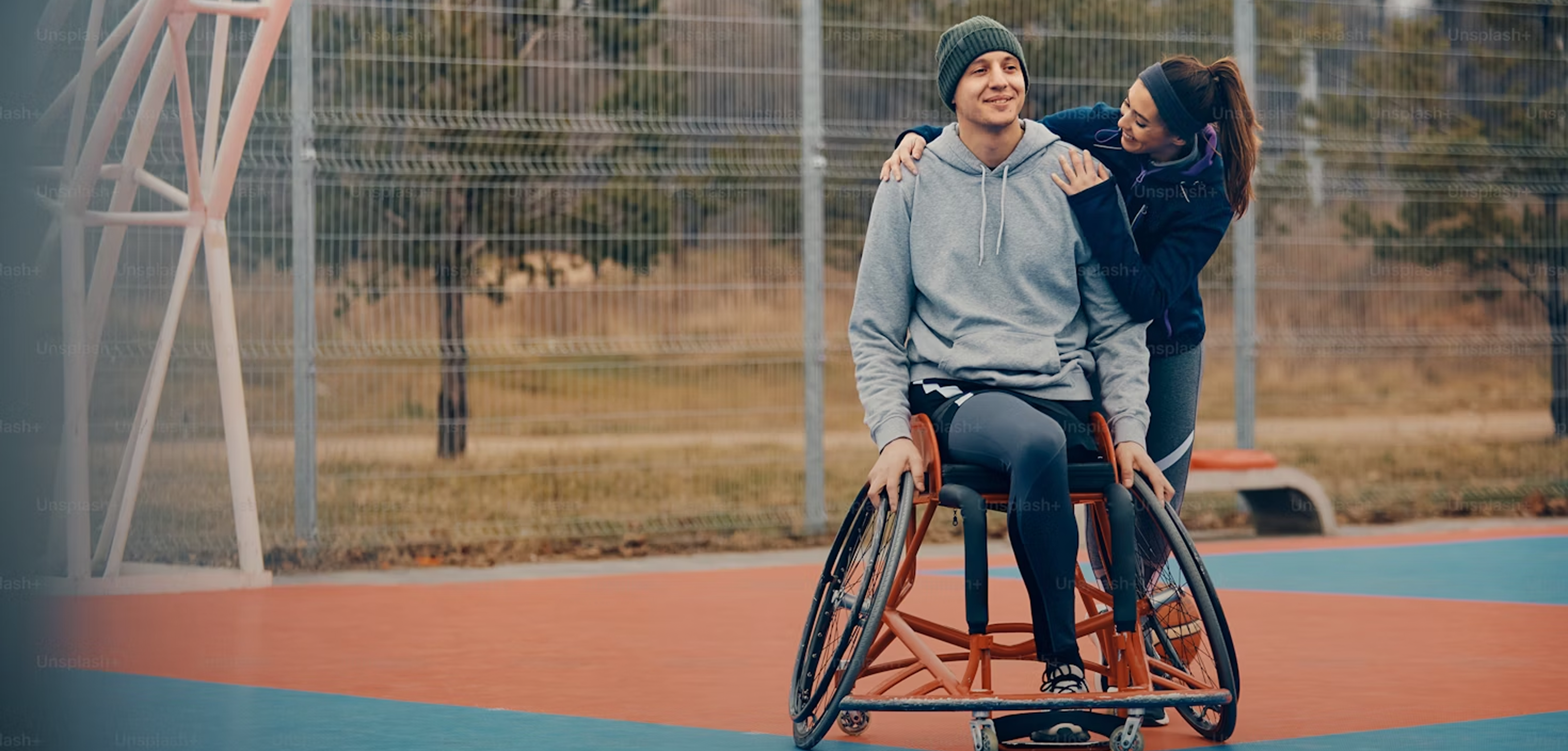 Happy couple on athletic track with wheelchair